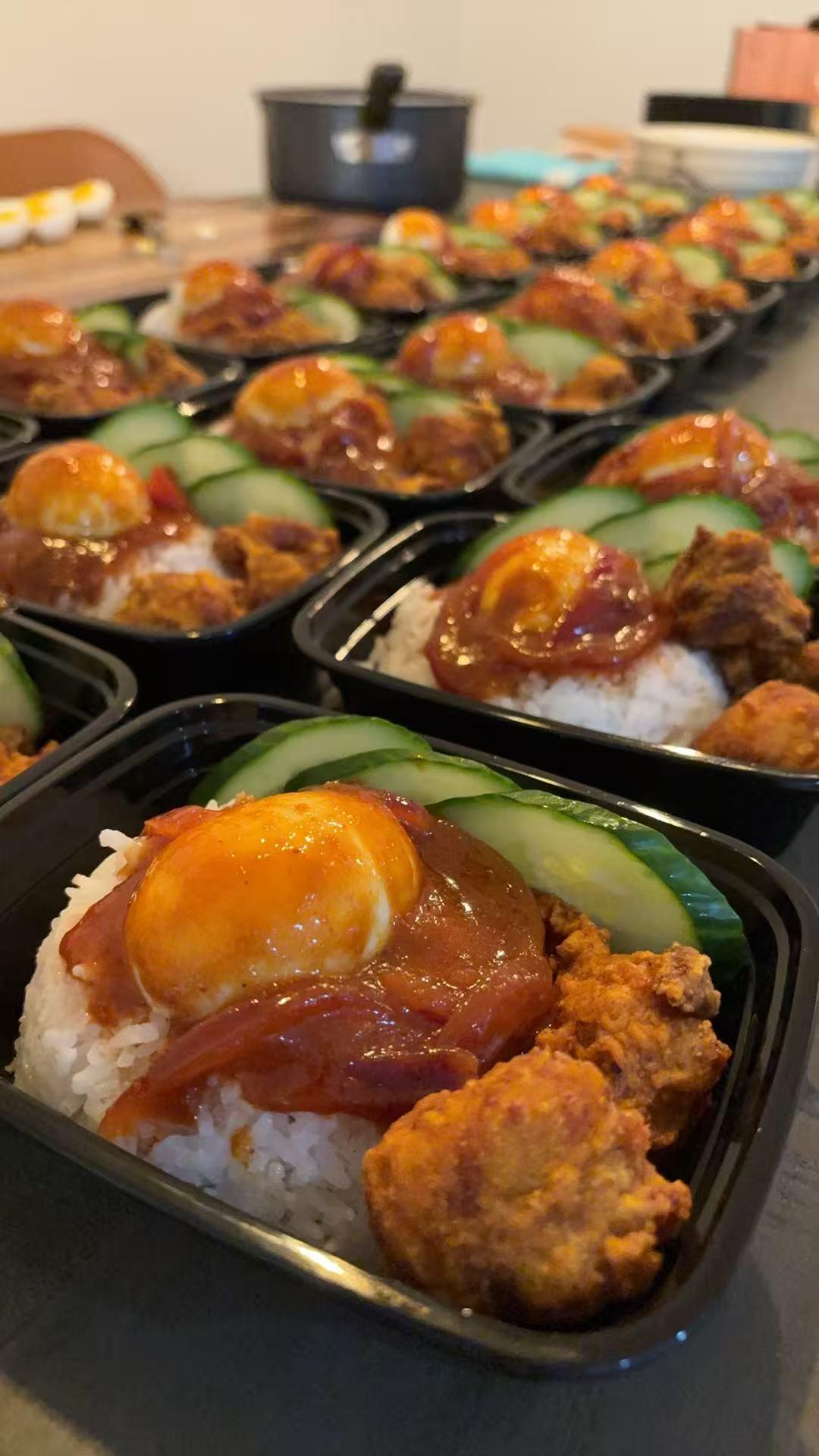 Rows of nasiGO boxes with coconut rice, sambal, egg, cucumber and crispy chicken