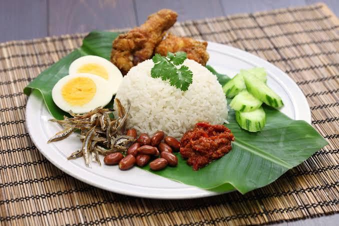 Close-up of a nasiGO box with sambal, egg and crispy chicken